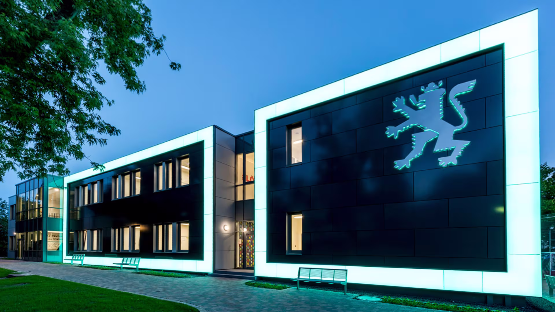 Das neue Schulhaus mit Leuchtrahmen in der Nacht
